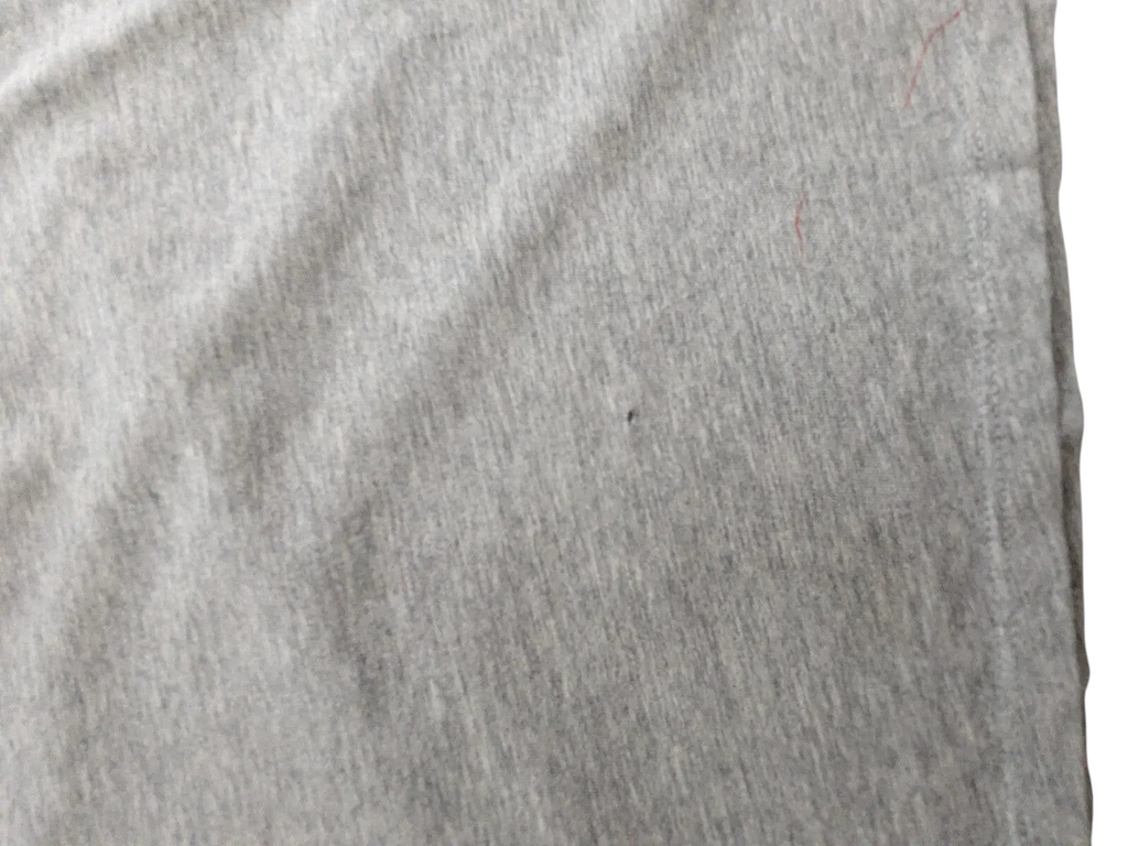 Close-up of grey cotton fabric on a My Store Nike t-shirt showing a small fabric flaw and minor wear