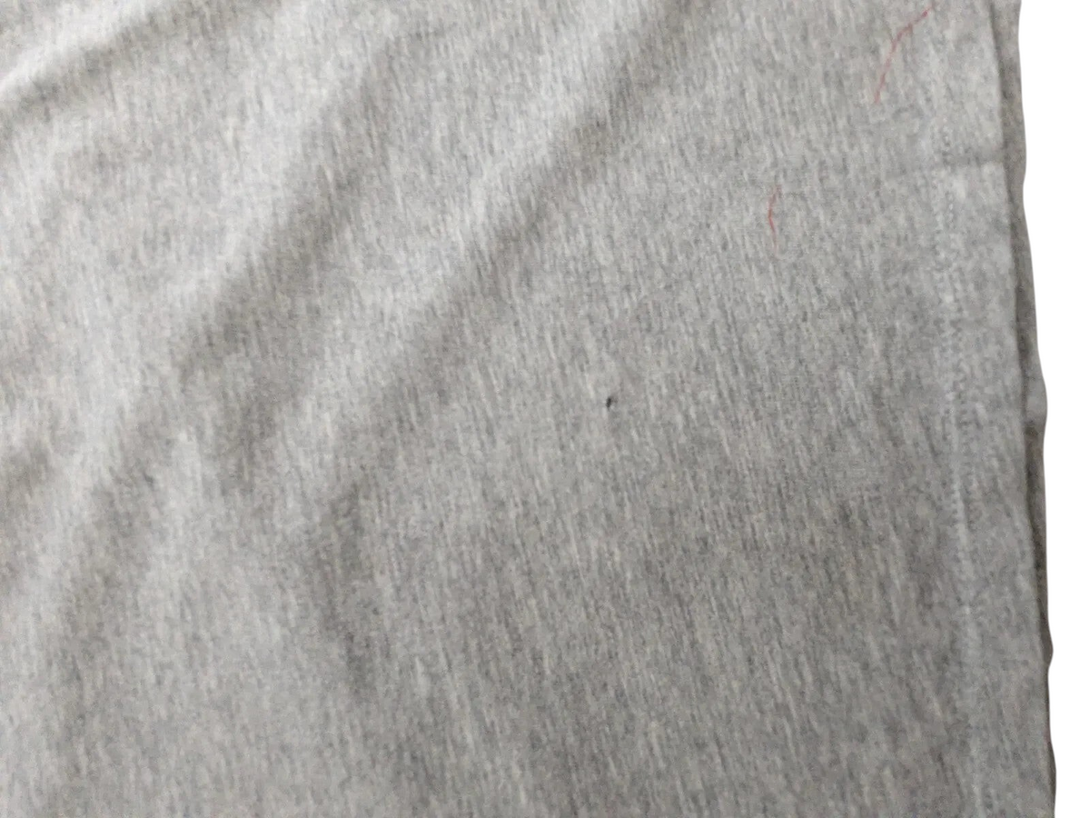 Close-up of grey cotton fabric on a My Store Nike t-shirt showing a small fabric flaw and minor wear